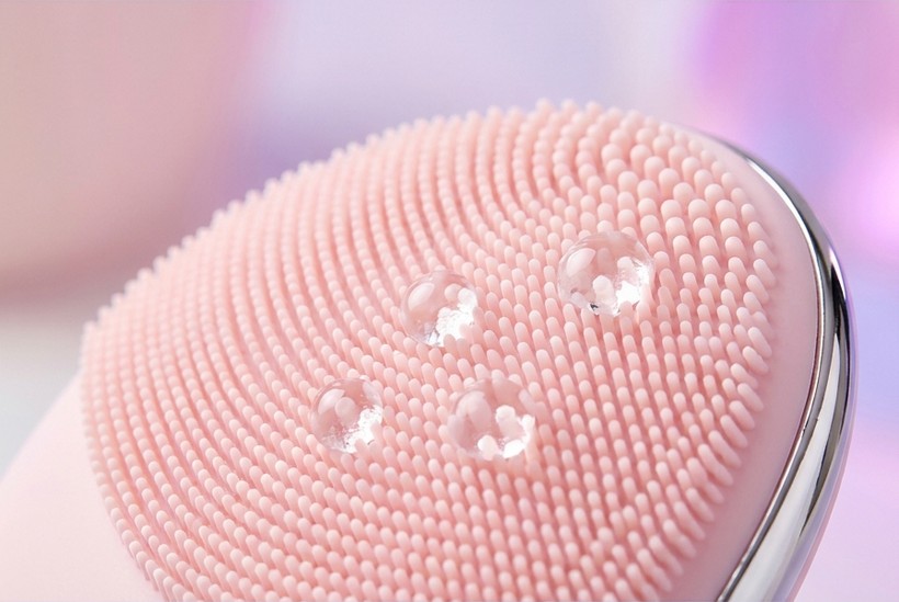 Bare pink silicone brush surface with clean water droplets beading on top